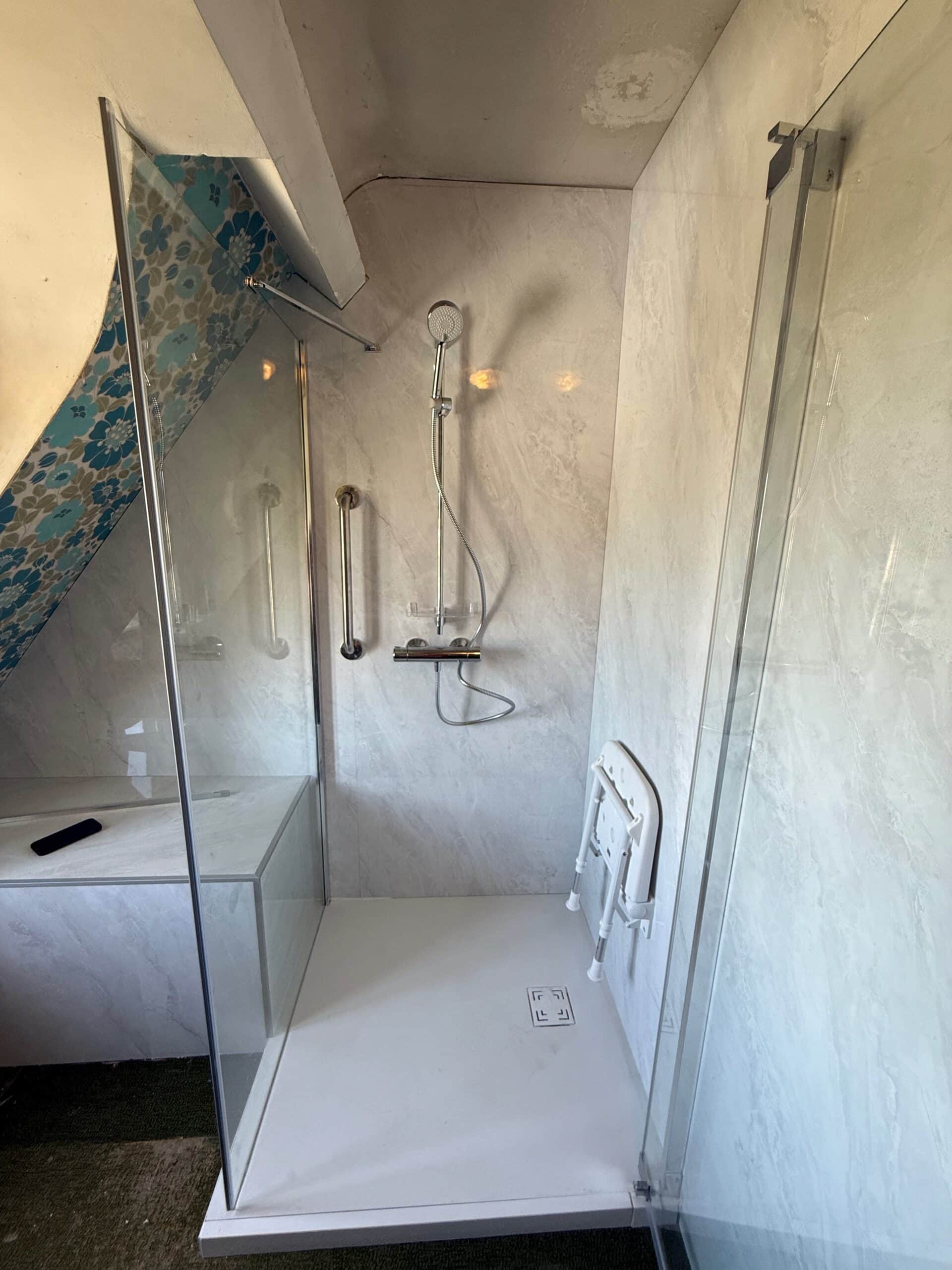 Douche senior avec siège et barre d'appui installée par Hyseco dans le Brabant wallon