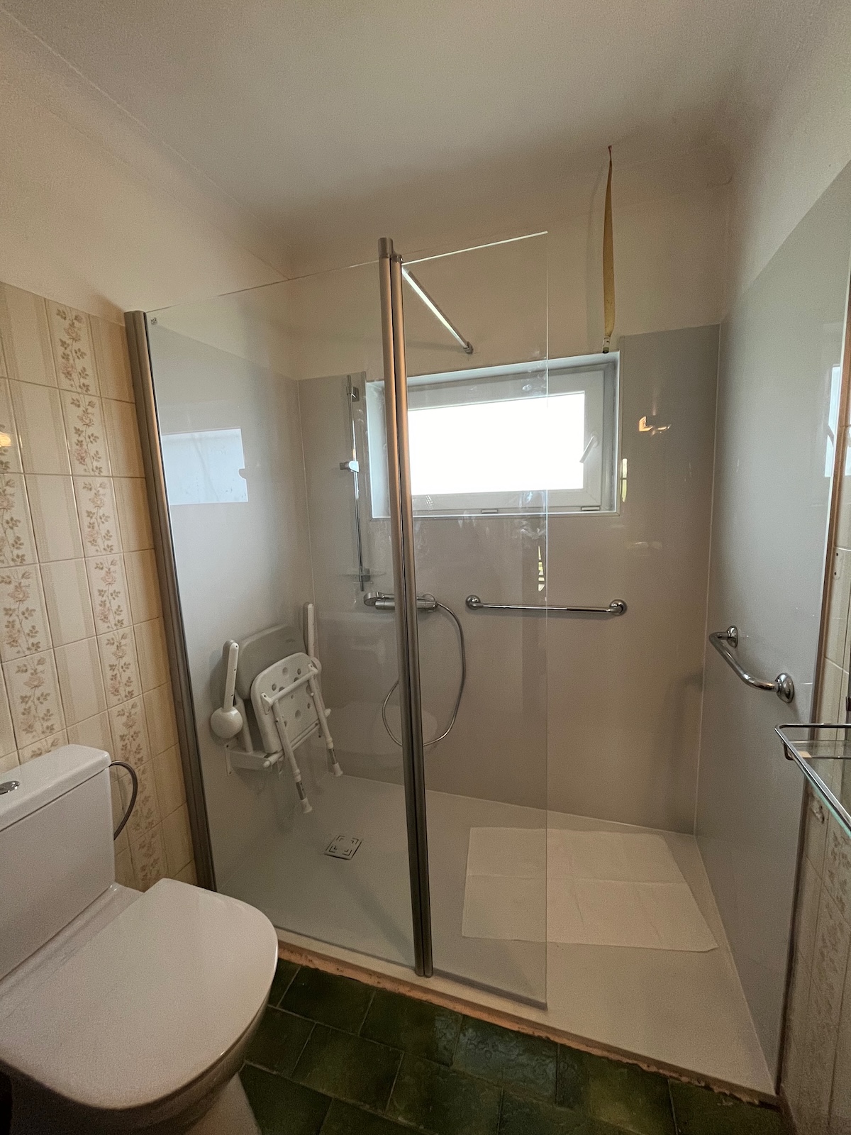 Douche accessible avec siège rabattable et barres d’appui installée par Hyseco à Liège