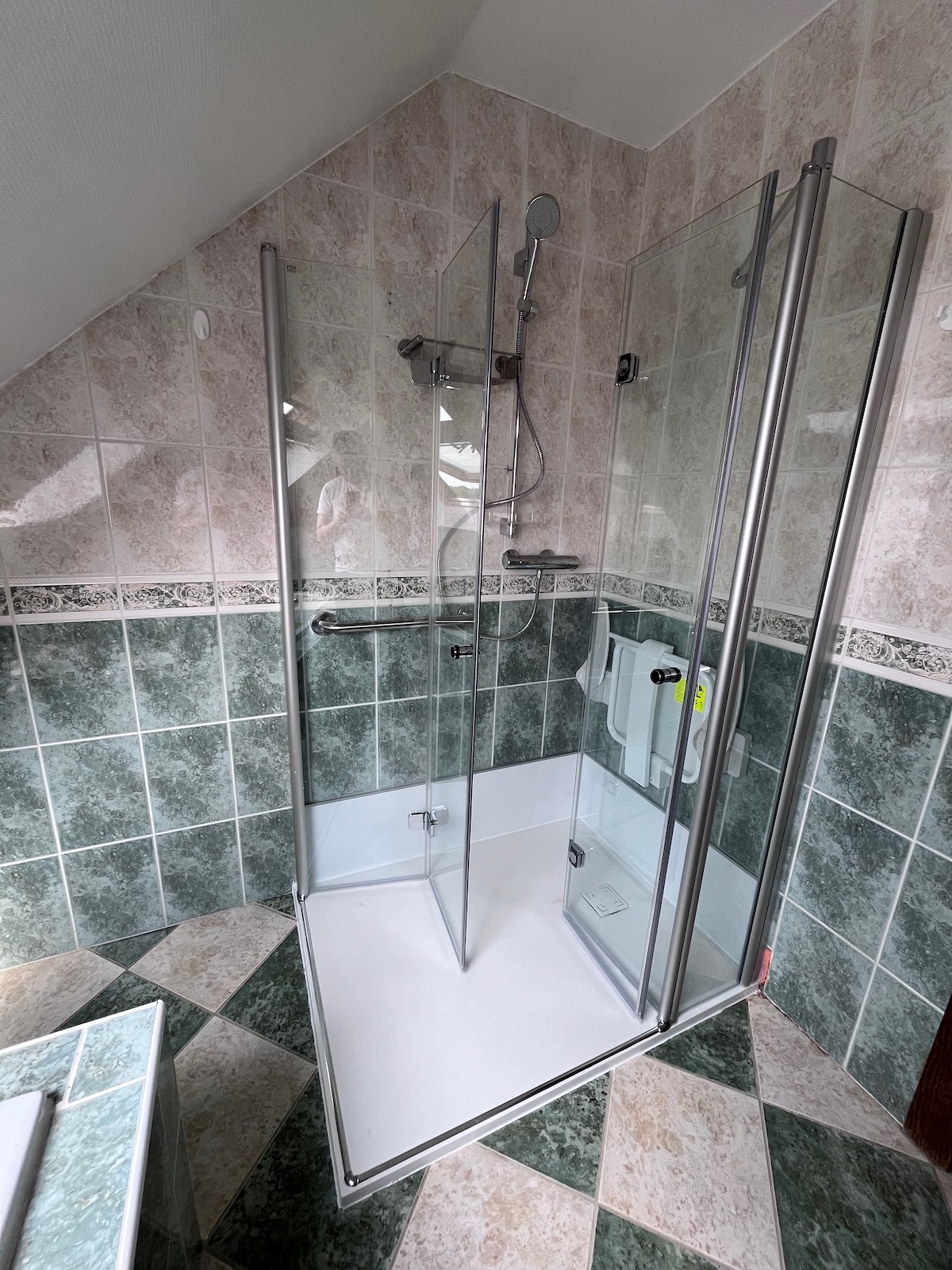 Douche senior accessible avec siège rabattable et barre d’appui installée dans le Hainaut