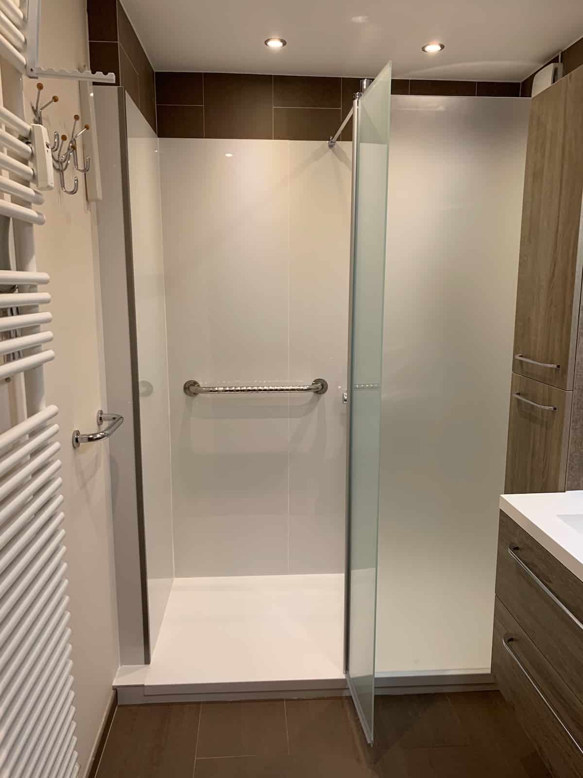 Douche senior accessible installée à Bruxelles avec receveur extra-plat et barre d'appui murale