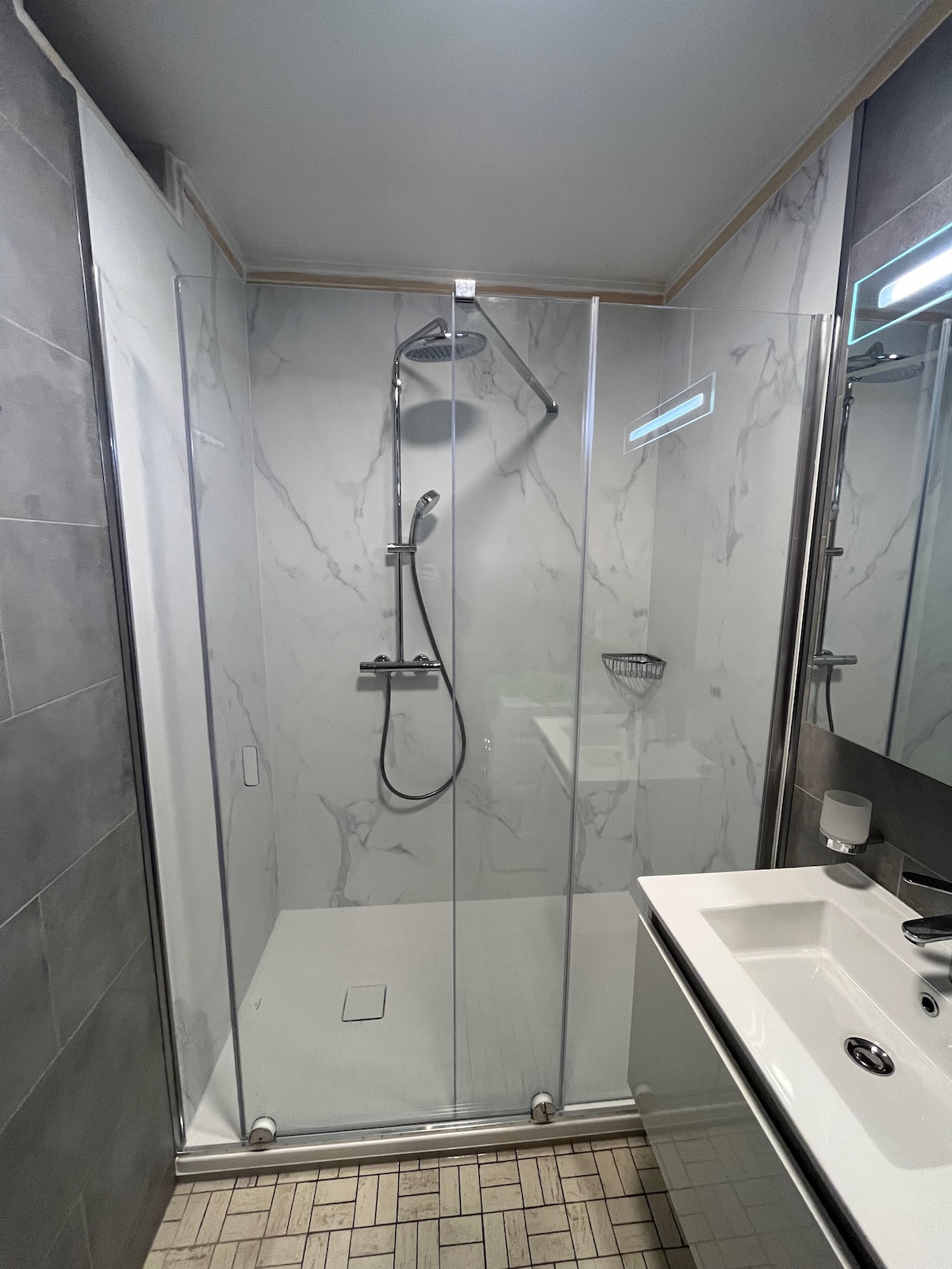 Douche senior accessible installée à Bruxelles avec receveur extra-plat et paroi en verre