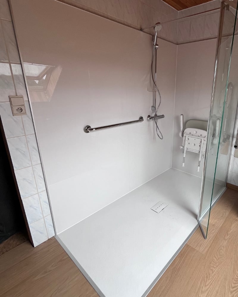 Douche senior de plain-pied avec receveur extra-plat, barres d'appui inox et paroi vitrée — réalisation Hyseco Belgique