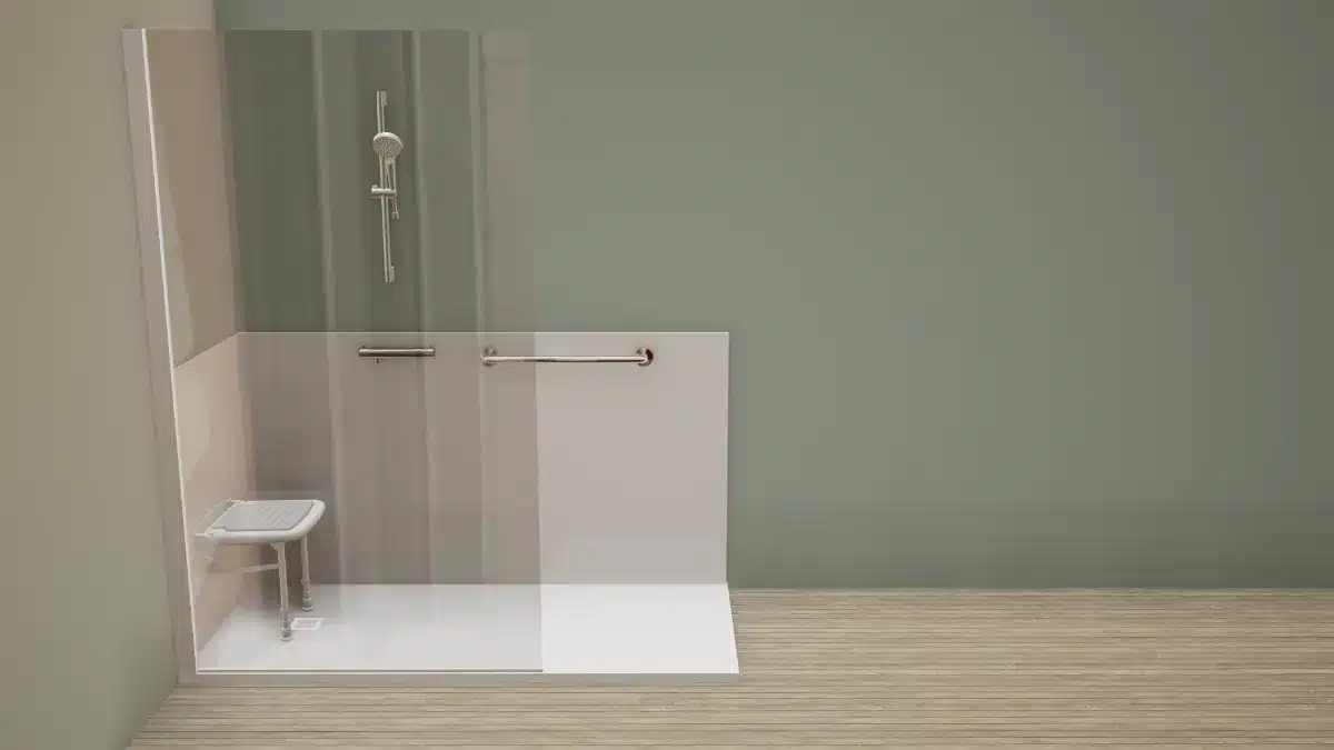 Accessible shower stall with a fold-down seat, grab bars, and a handheld showerhead against a light gray wall. A glass panel separates the shower area from the room.